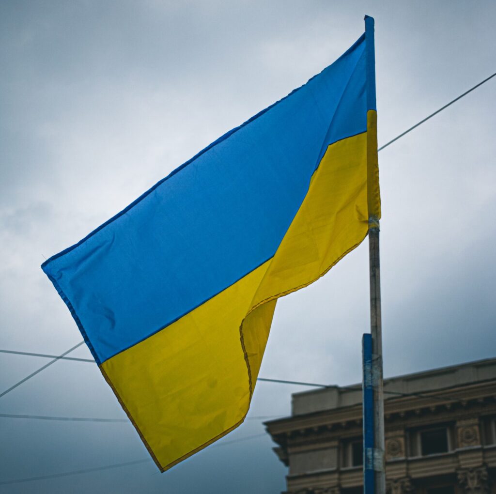 Ukrainian flag waving against a cloudy sky, supporting charities helping in Ukraine.